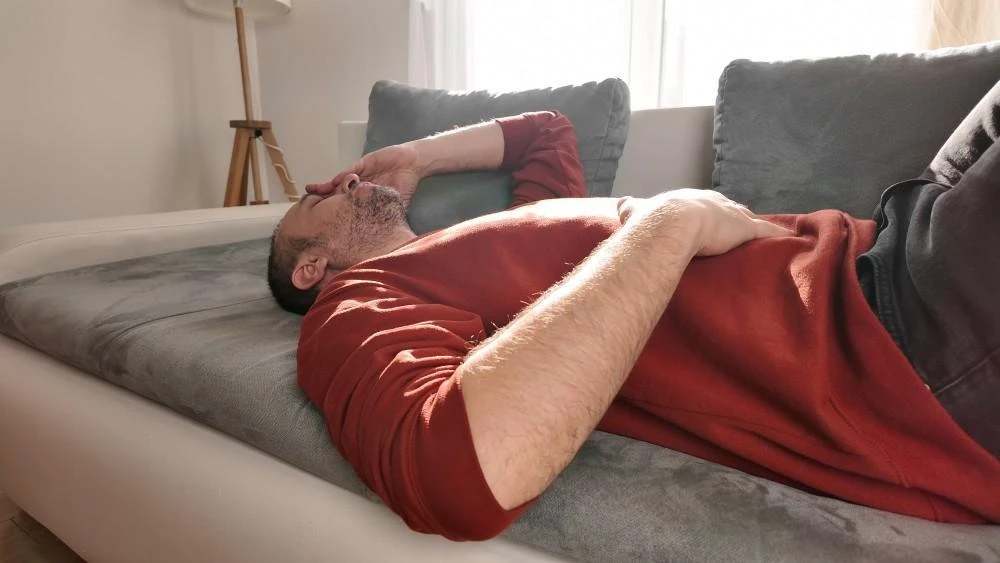 Man lying in bed holding his lower abdomen in pain